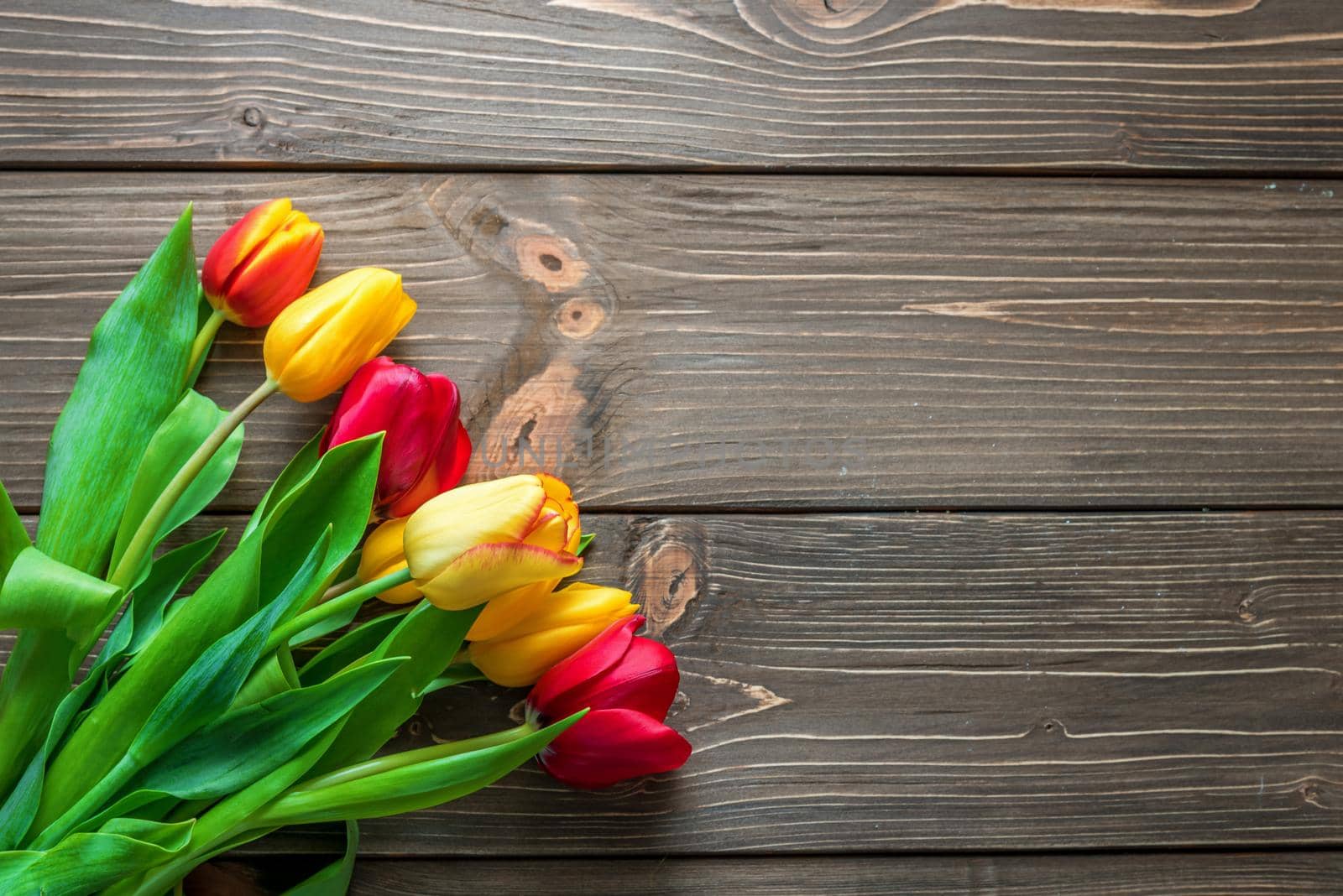  Bouquet of tulips in a paper shopping bag on a wooden background, concept of discounts and sales on the Women's Day or Mother's Day or Easter