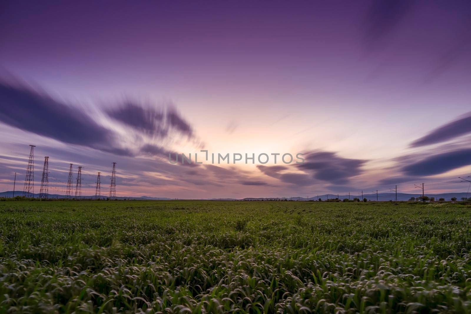 Green field and cloudy sky, long exposure at sunset 
