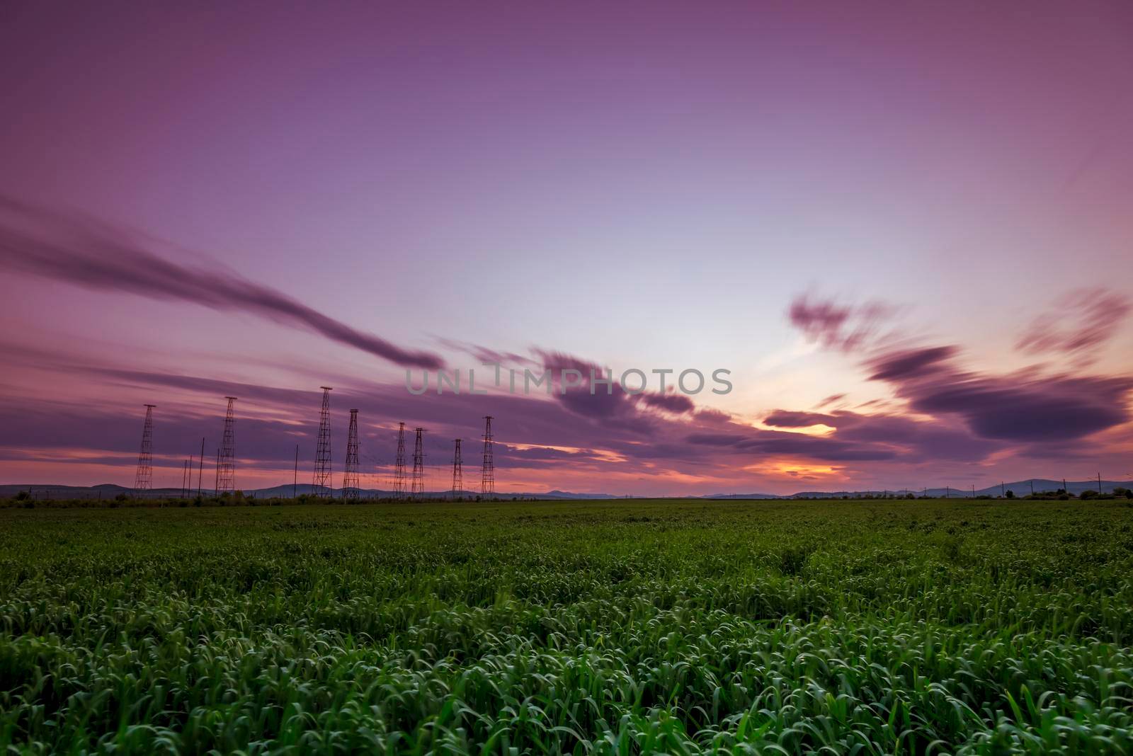 Green field and cloudy sky, long exposure at sunset