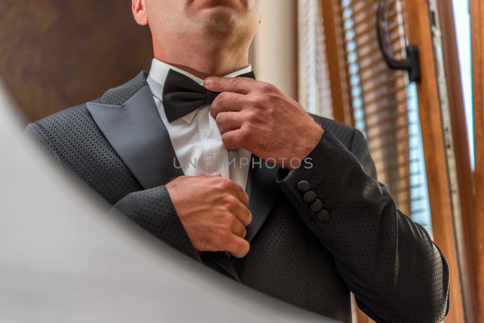 Male hands correct wedding bowtie on white shirt