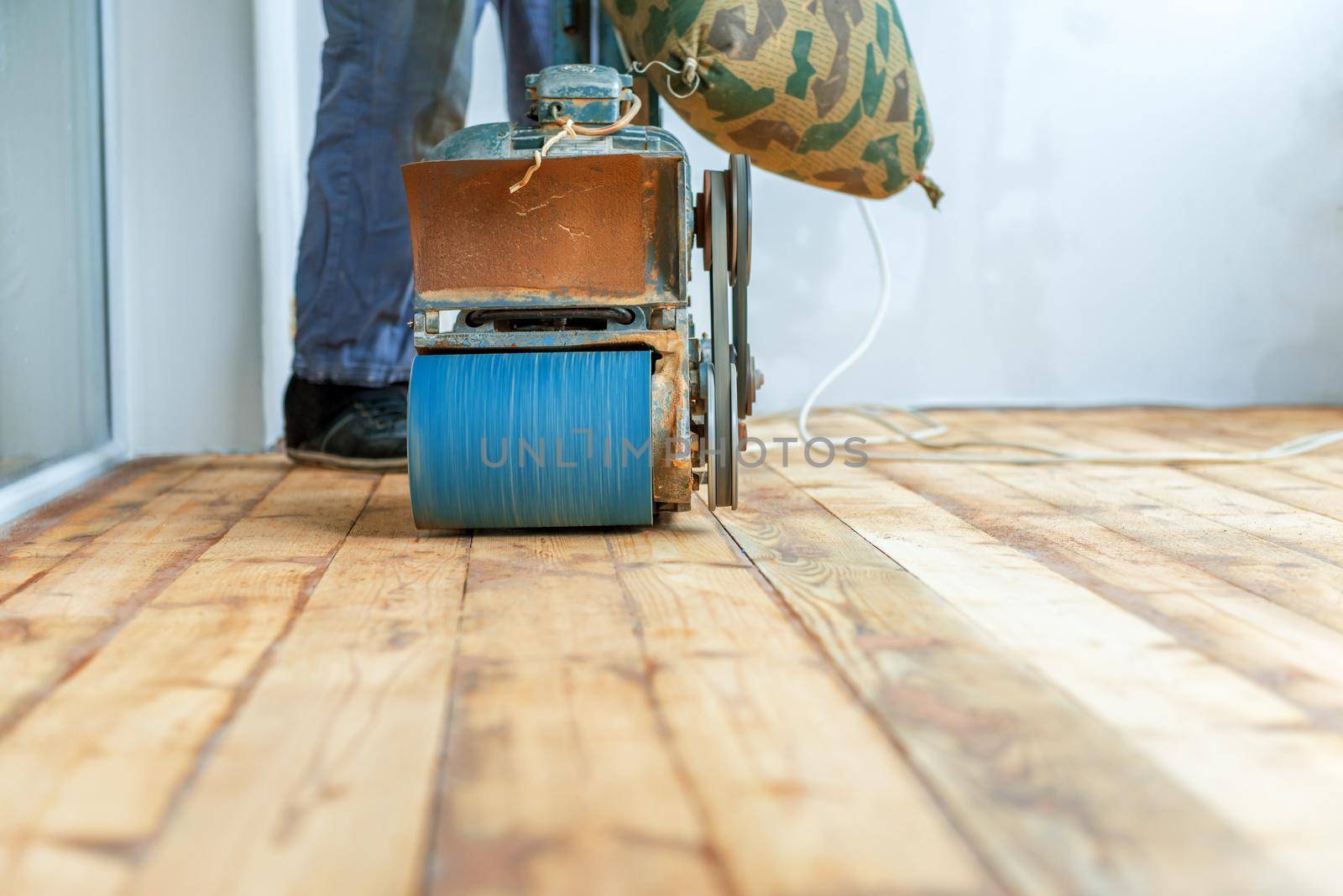 Worker polishing parquet floor with grinding machine