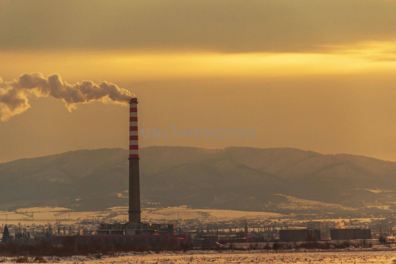 smoke out of the pipe at the factory, in winter, at sunset.