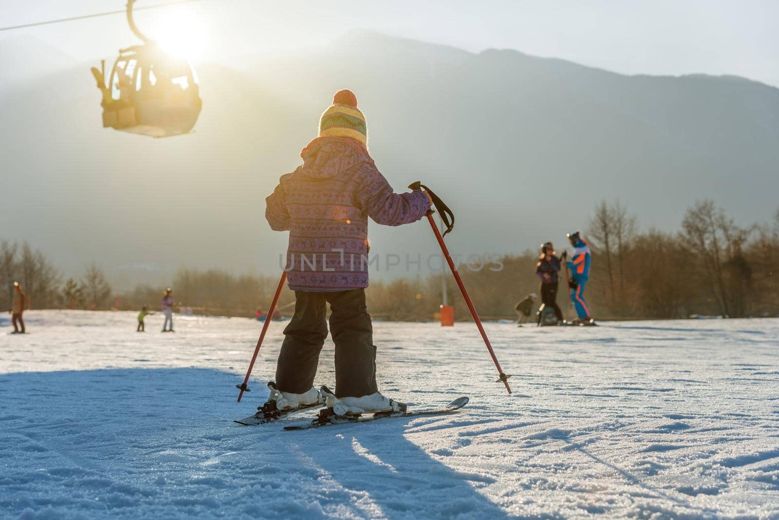 Little boy skiing down the hill at sunset