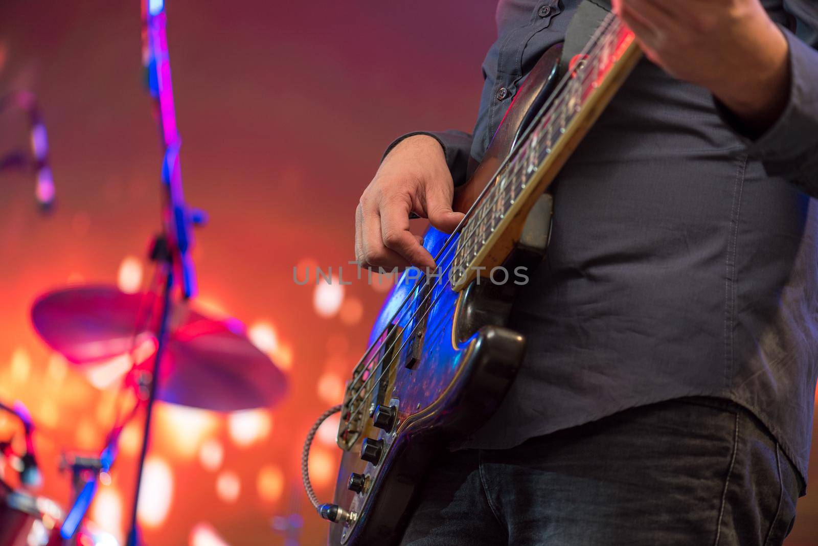 Man playing guitar on a stage musical concert close-up view.