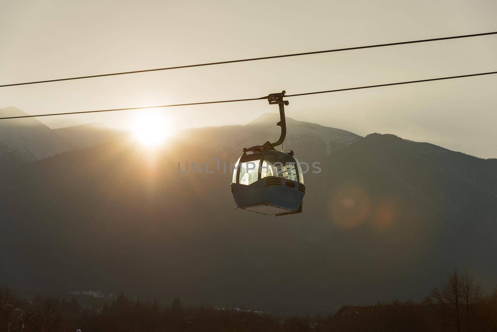 Ropeway and cable car transport system for skiers in sunset.
