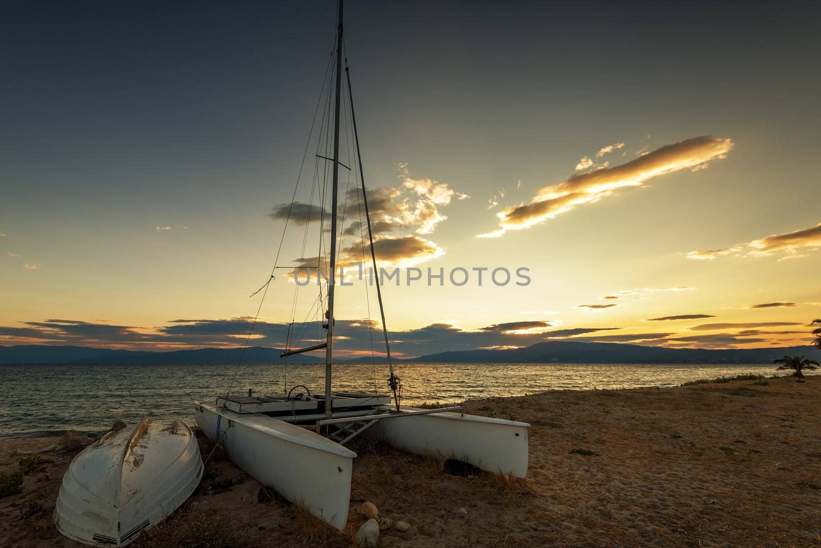 Sailboat on the beach at sunset in Greece.