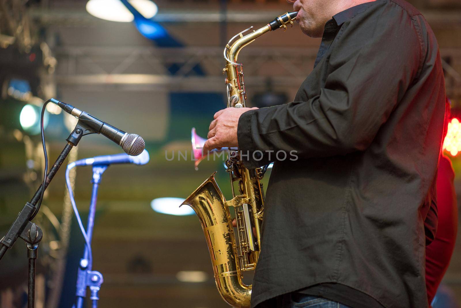 Musicial music live band performing on a stage with different lights. Saxophonist plays.