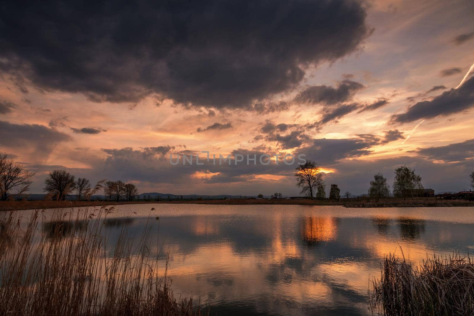 Sunset over calm lake , sky reflection in water in summer 