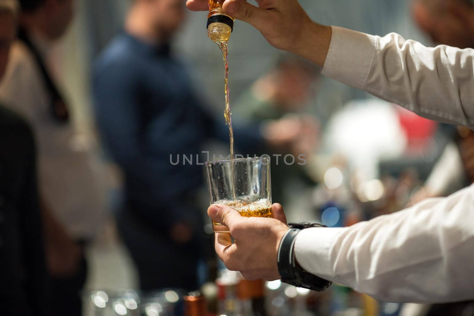 The barman pours alcohol into a glass. Close-up.