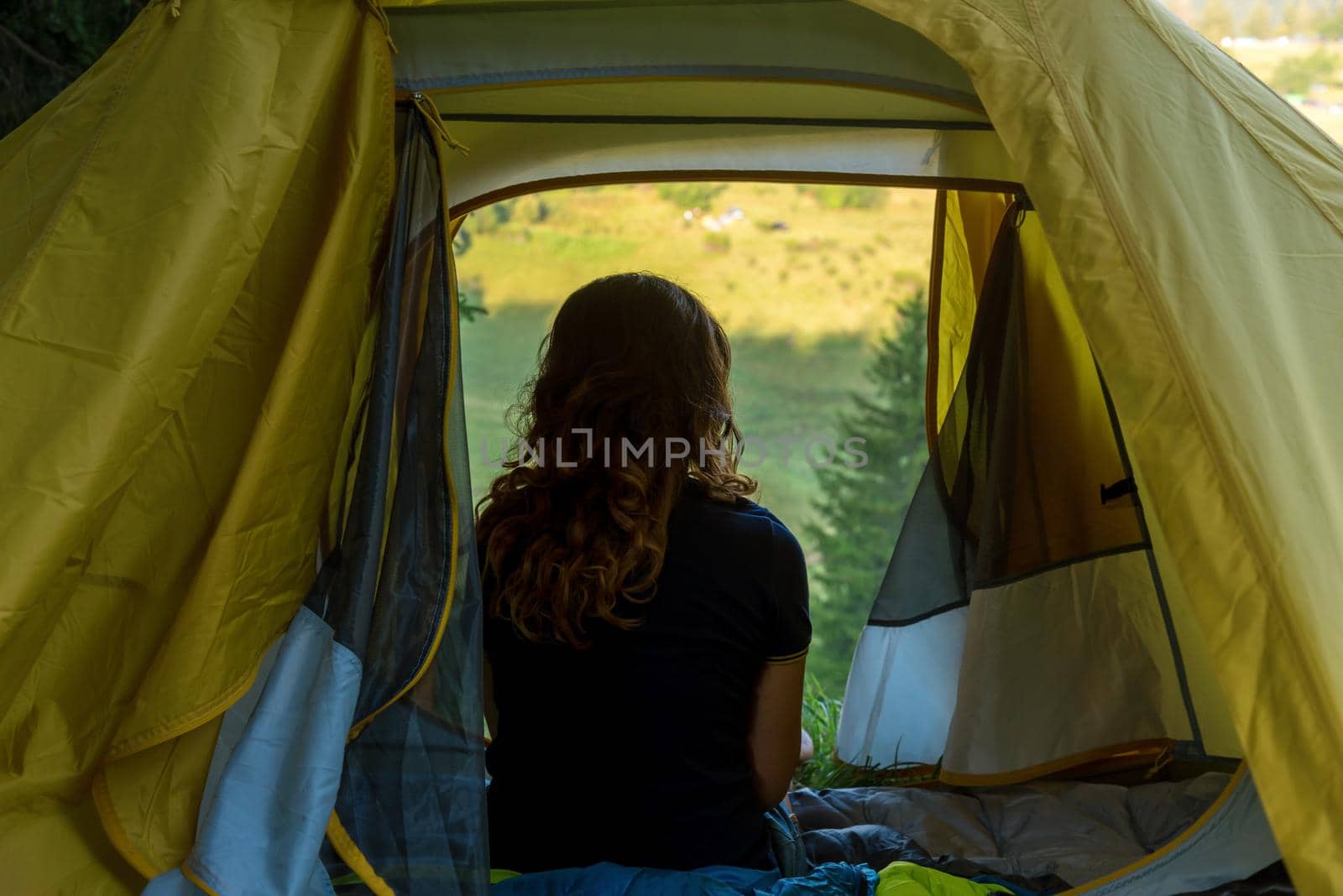Young Woman rest in a tent with a view of the mountain landscape in summer 