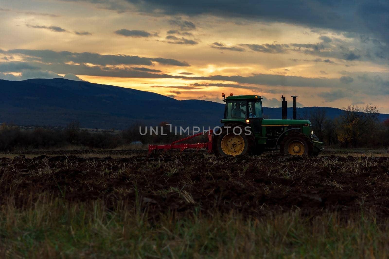 Tractor in sunset plowing the field.