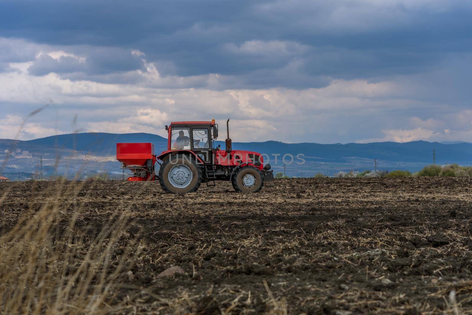 Tractor spreading artificial fertilizers in spring