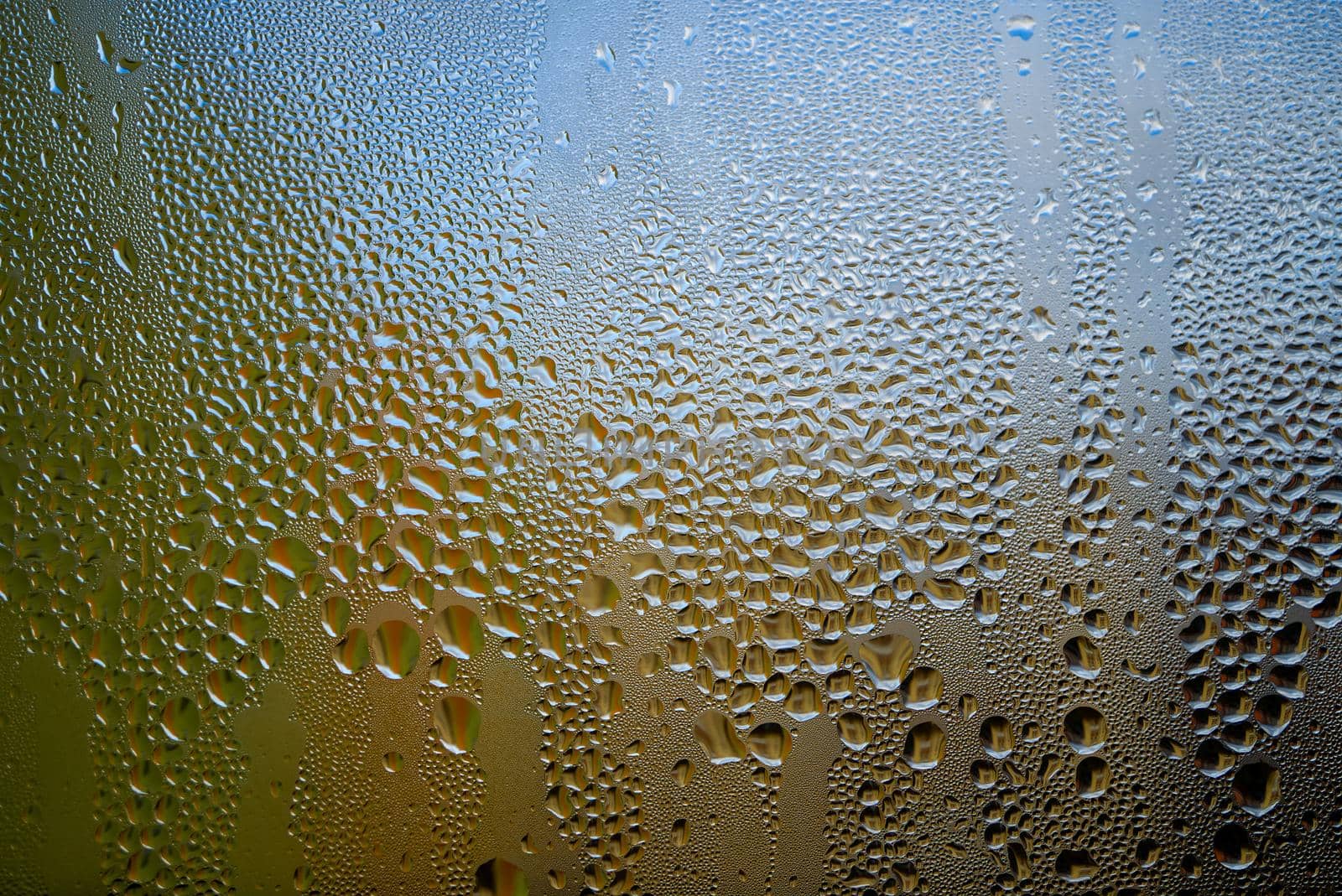 Condensation with beaded moisture droplets on the outside of a cold glass or bottle in a close up full frame background texture