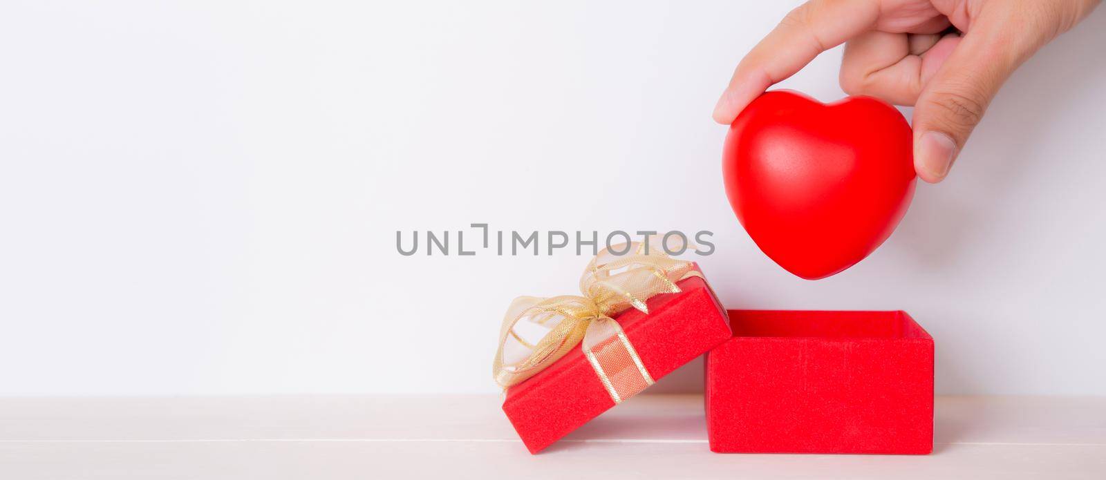 Valentine day, hand open red gift box put heart, celebration and anniversary with giving love, donate and aid with heart shape symbol, charity and health, copy space, holiday and festive concept. by nnudoo