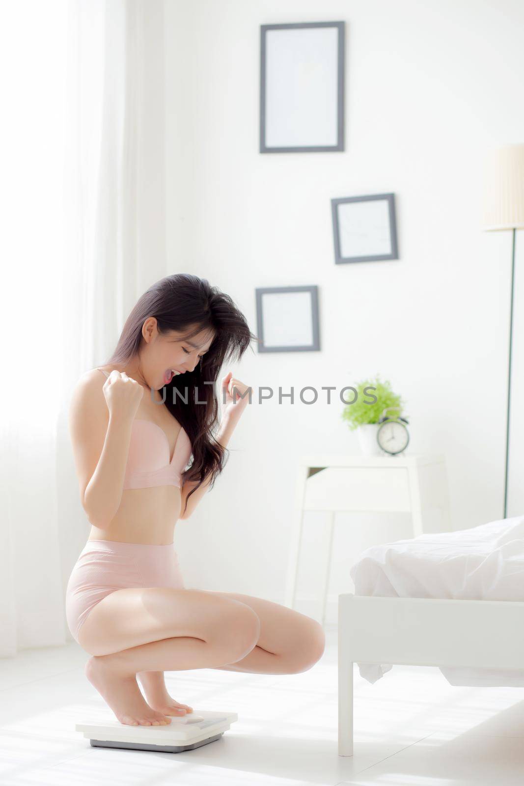 Beautiful young asian woman sexy body happy sitting on scales abdomen for control weight loss with success at room, beauty girl belly thin cheerful have cellulite with diet with excited.