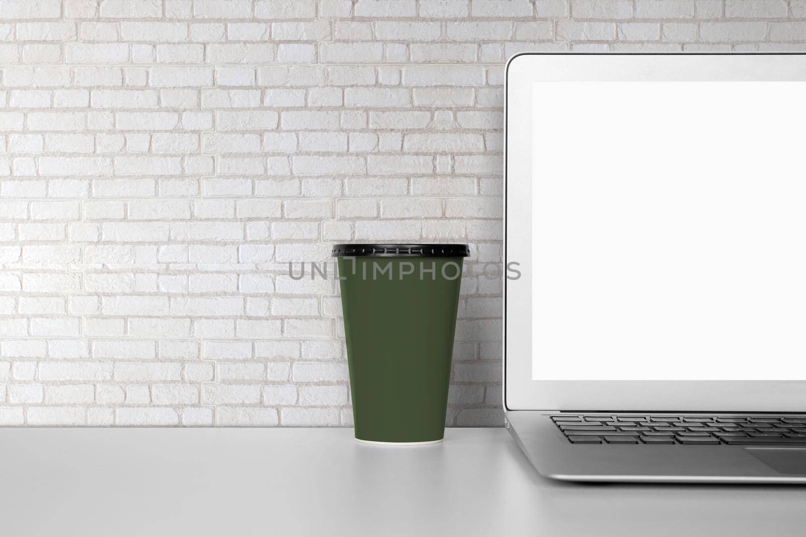 Mockup template laptop computer display screen and cup with blank on desk, workplace and office, interior room, indoor, copy space, business and workspace concept.
