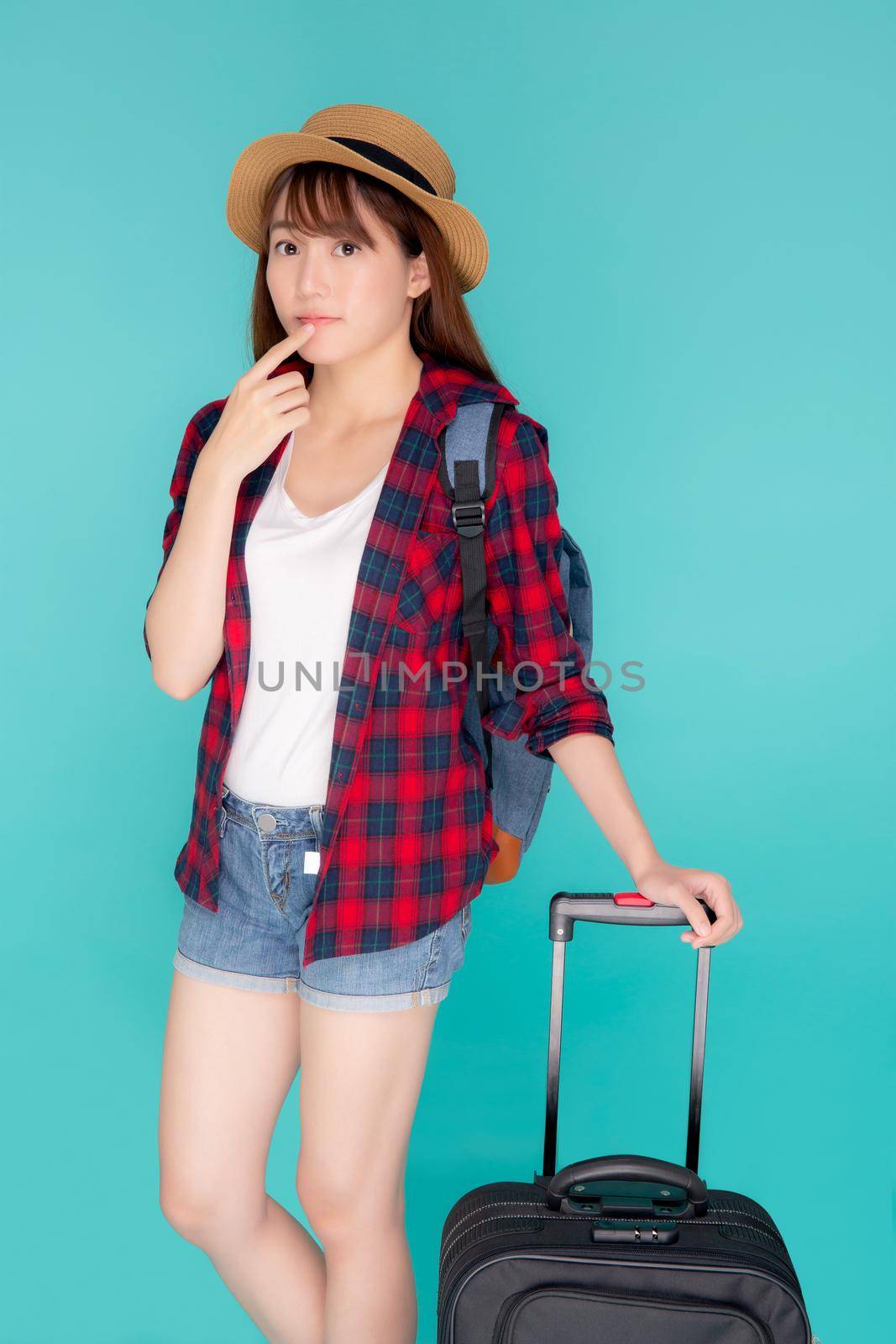 Beautiful young asian woman pulling suitcase isolated on blue background, asia girl having expression is cheerful holding luggage walking in vacation with excited, journey and travel concept. by nnudoo