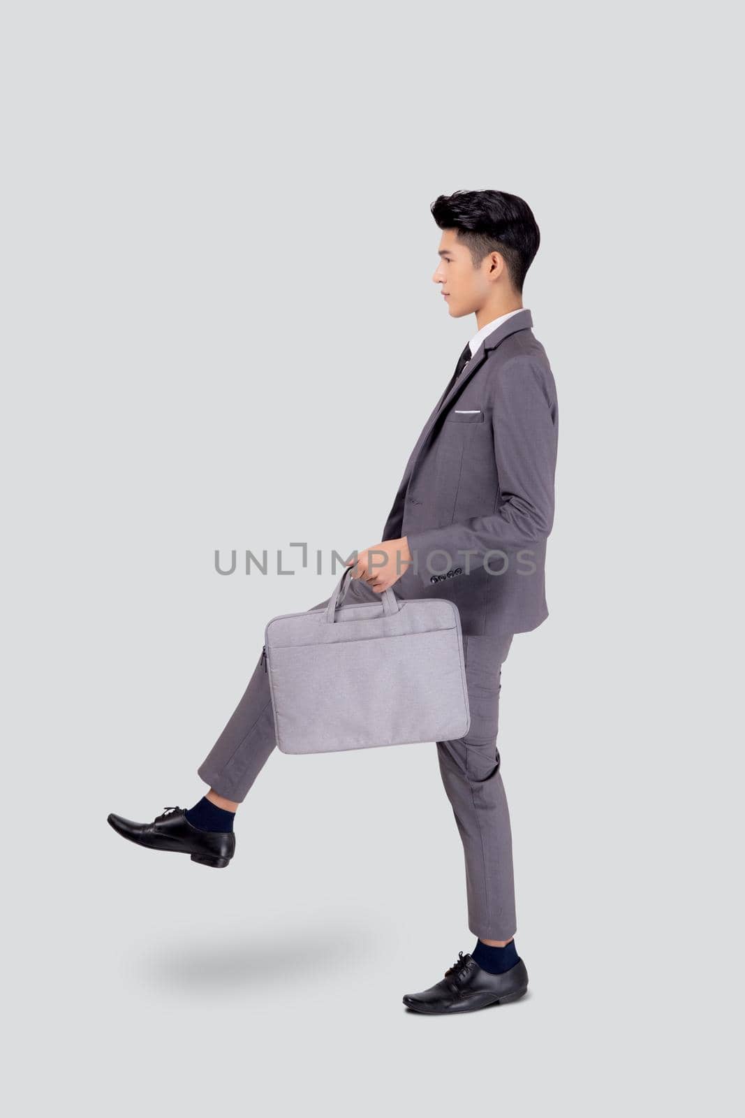 Young asian business man in suit walking movement holding bag isolated on white background, portrait of executive or manager, happy businessman holding briefcase, male with confident for success.