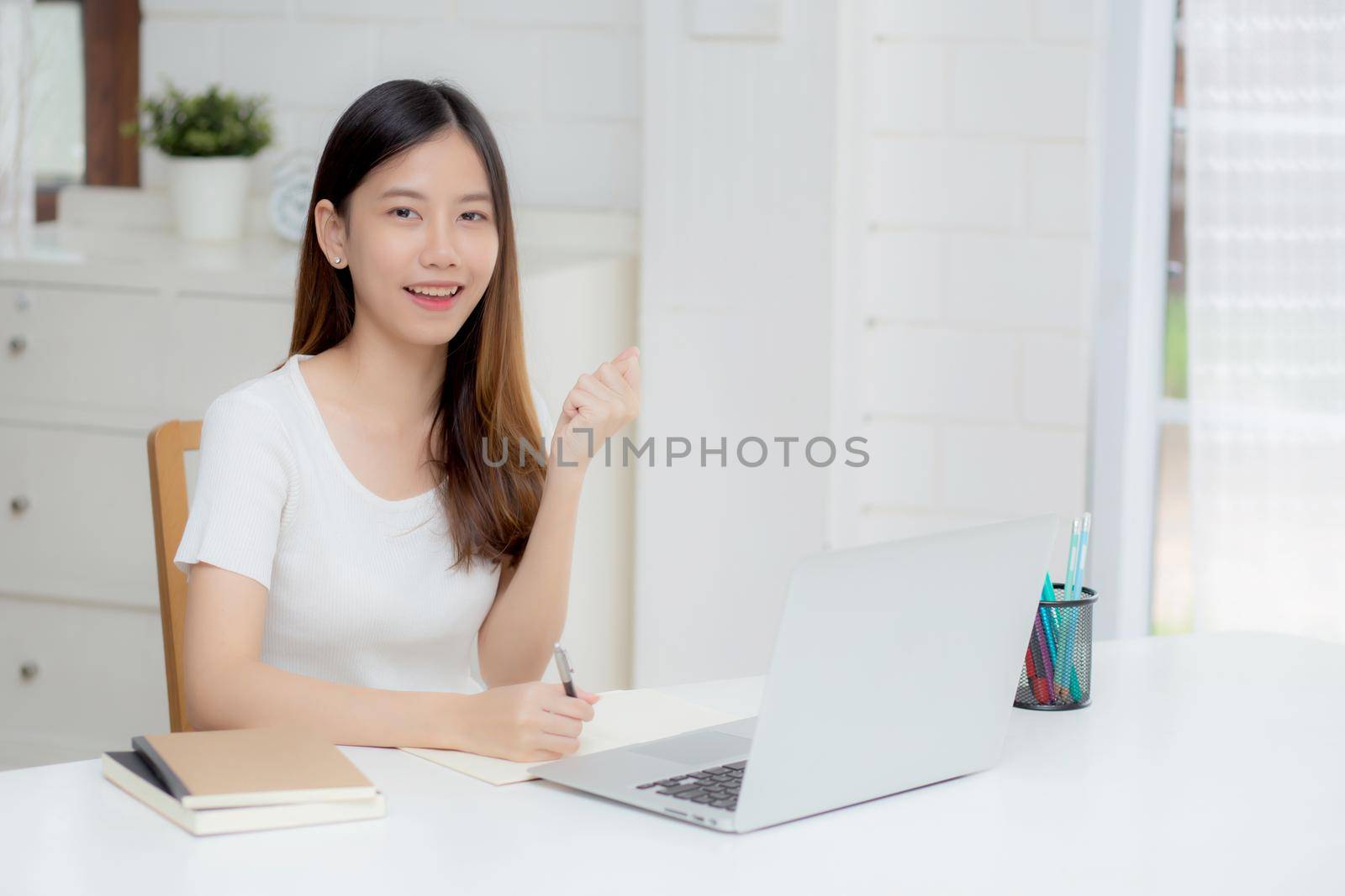 Young asian woman confident working at home with laptop computer and thinking idea for planning, freelance happy girl excited and success using notebook thoughtful and writing, business concept.