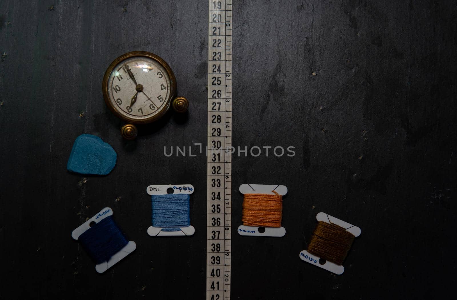 Black background with sewing utensils and a clock