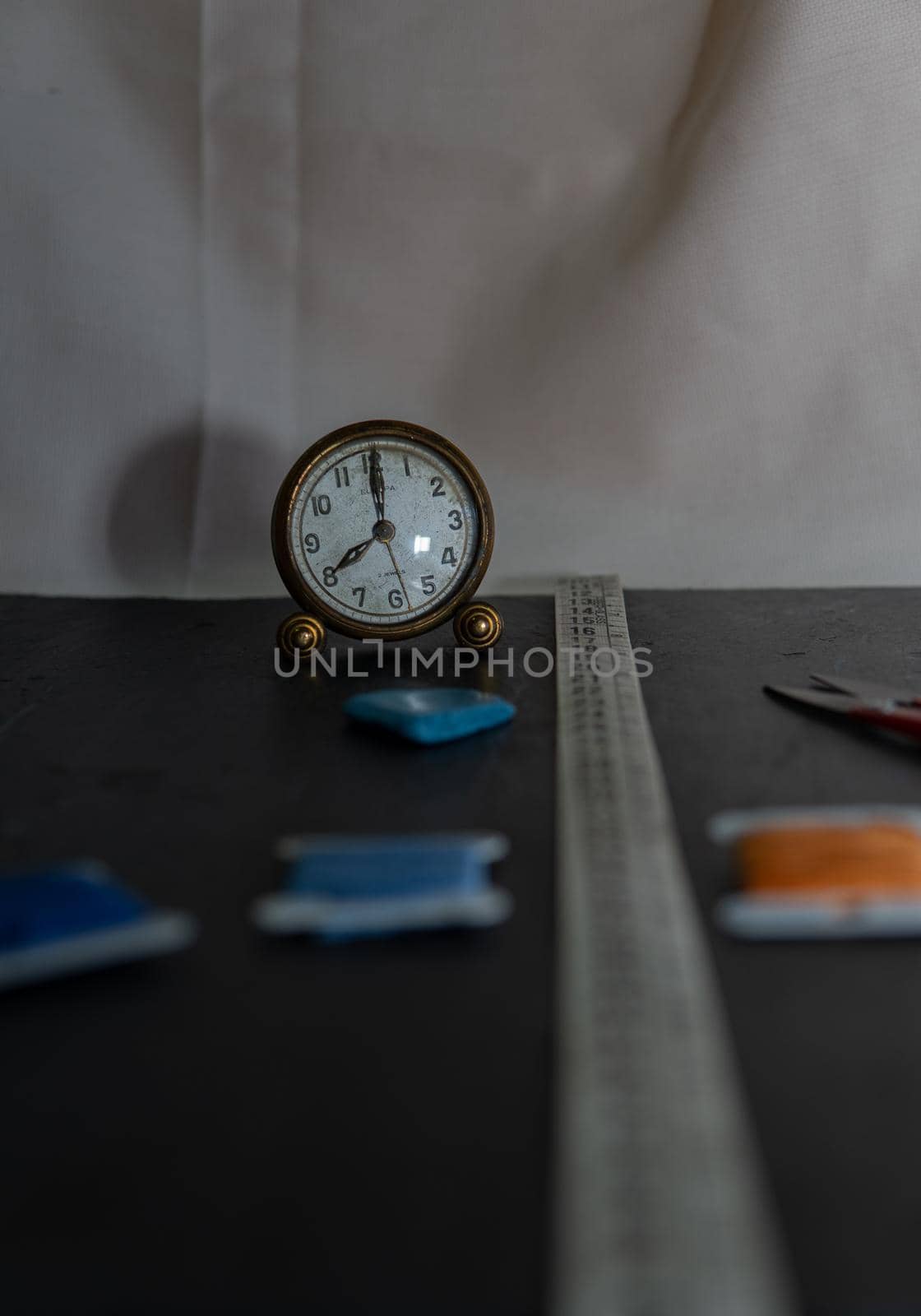 Black background with sewing utensils and a clock