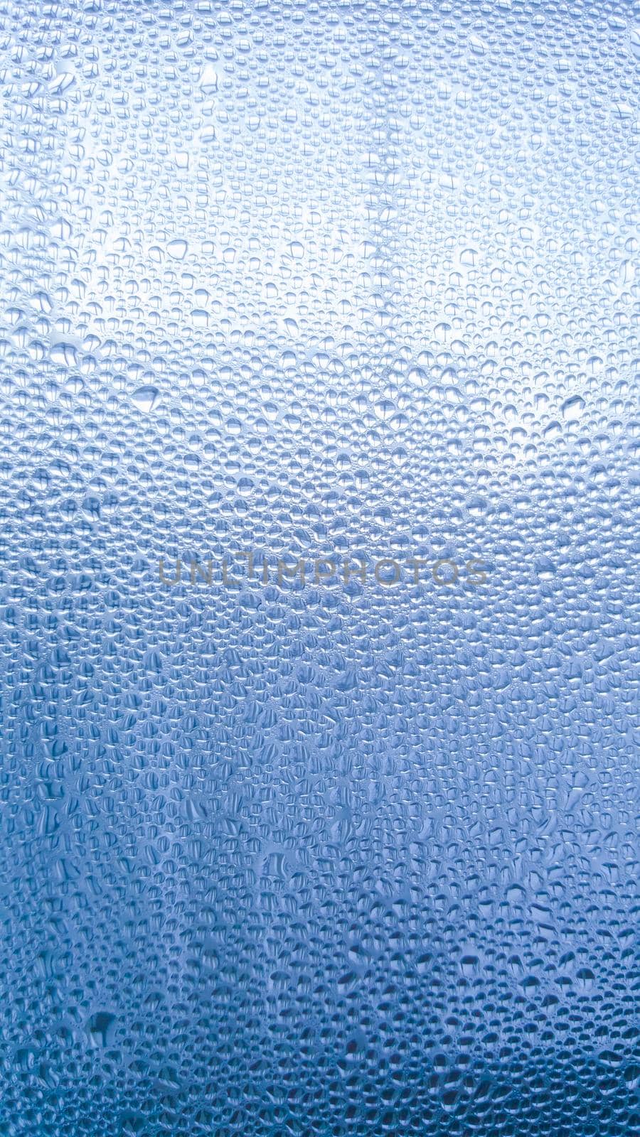 Raindrops on the glass in rainy weather.The glittering, shiny surface of water on glass.Water drops in the form of balls or spheres.Blue raindrops background. Abstract backgrounds ornament with water