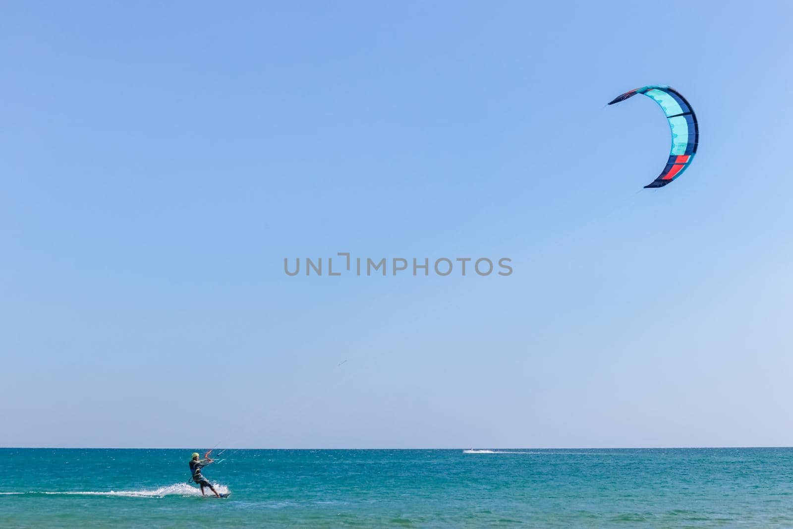 a kitesurfer surfing on the smooth azure water. recreational sport. A Man Rides A Kiteboarding In The Sea Water. extreme sport. High quality photo