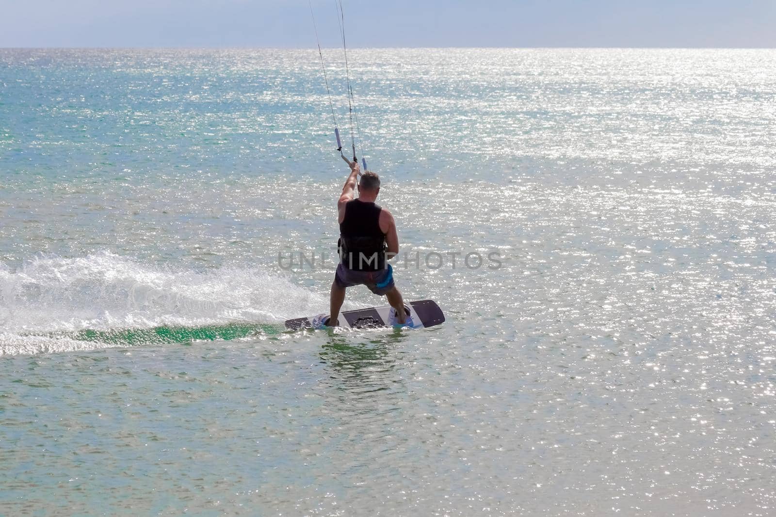 a kitesurfer surfing on the smooth azure water. recreational sport. A Man Rides A Kiteboarding In The Sea Water. extreme sport. High quality photo