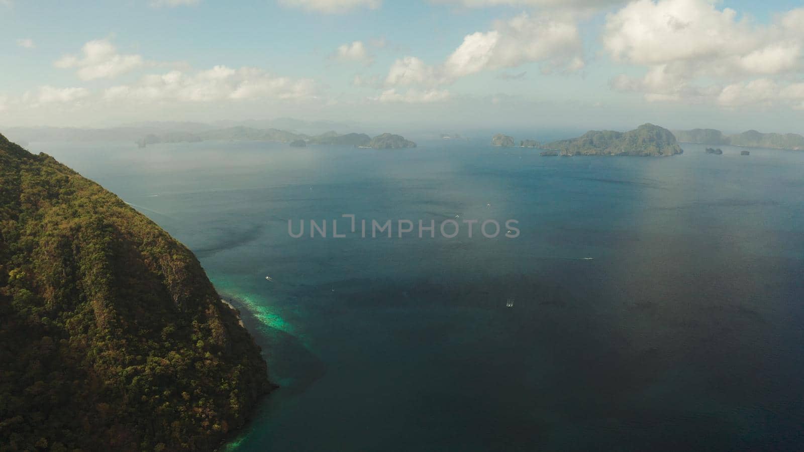 Seascape with tropical bay, rocky islands, ocean blue water, aerial view. islands and mountains covered with tropical forest. El nido, Philippines, Palawan. Tropical Mountain Range