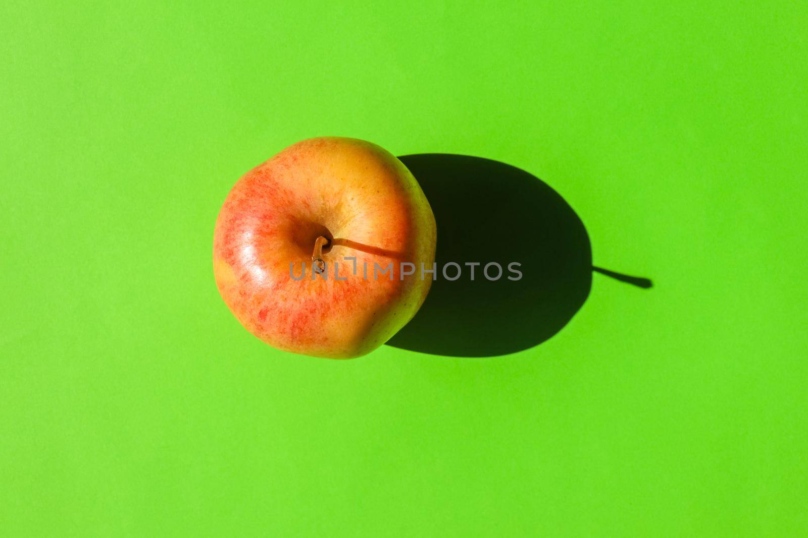 an Apple with a hard shadow on a plain background. the view from the top. blank for the pattern. High quality photo