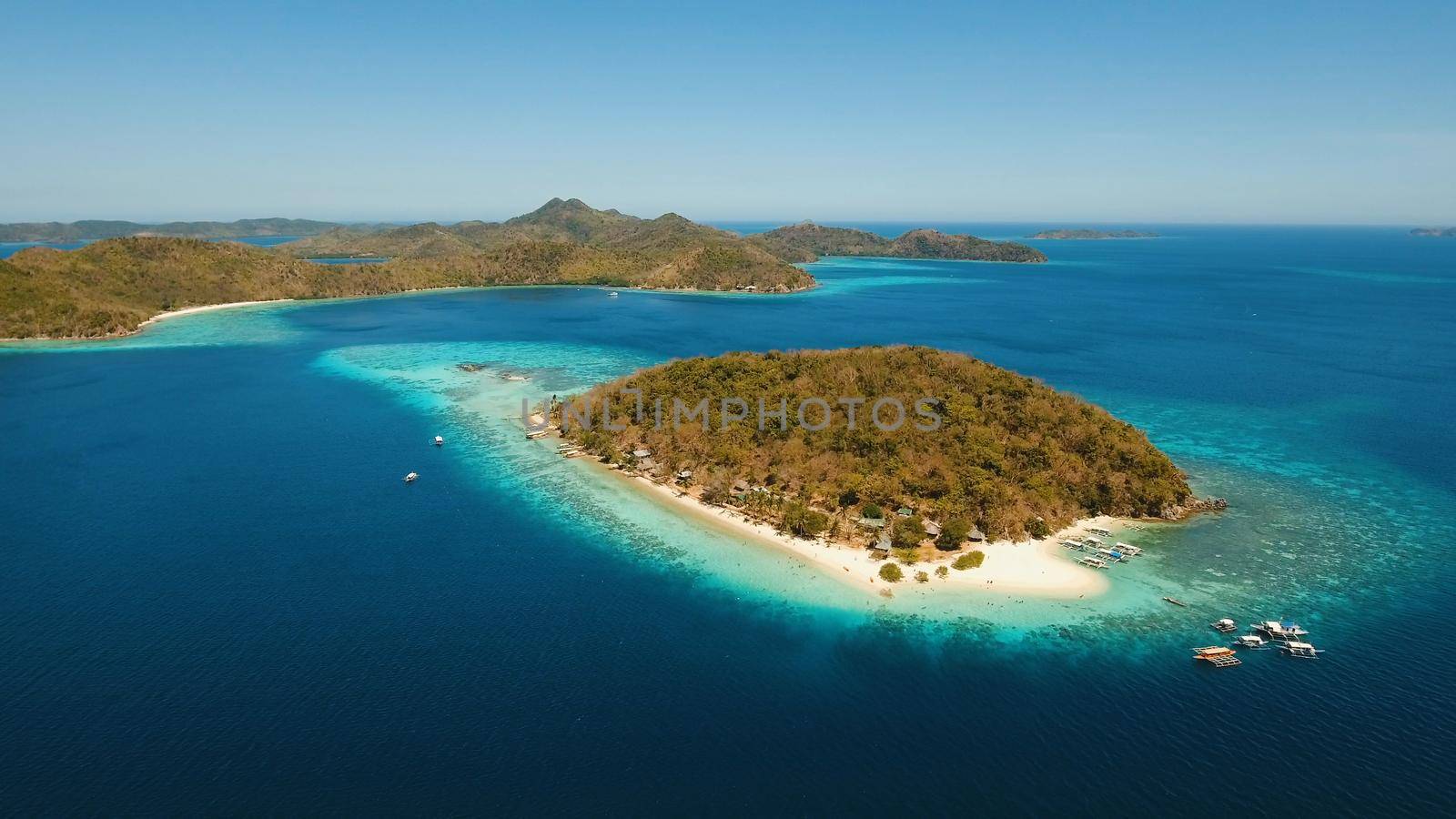 Aerial view of tropical beach on the island Banana, Philippines. Beautiful tropical island with sand beach, palm trees. Tropical landscape: beach with palm trees. Seascape: Ocean, sky, sea. Travel concept.