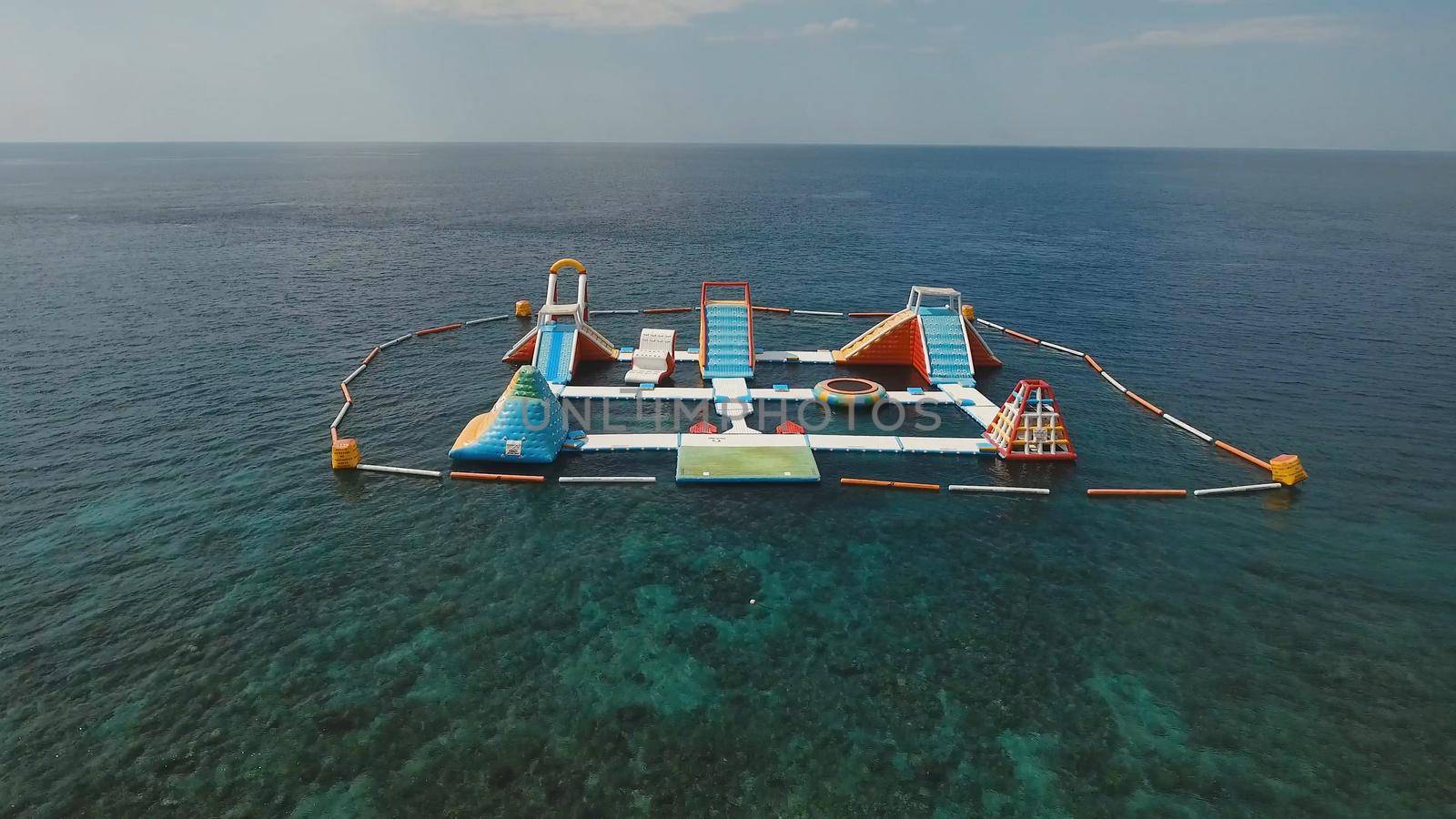 Aerial view inflatable Floating Water Park in the sea. Aquapark with slides and attractions in the ocean. Bali, Indonesia.