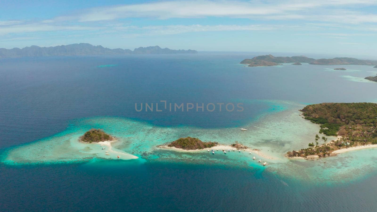 aerial seascape bay with tropical island and sand beach, turquoise water and coral reef. Bulog Dos, Philippines, Palawan. tourist boats on coast tropical island.