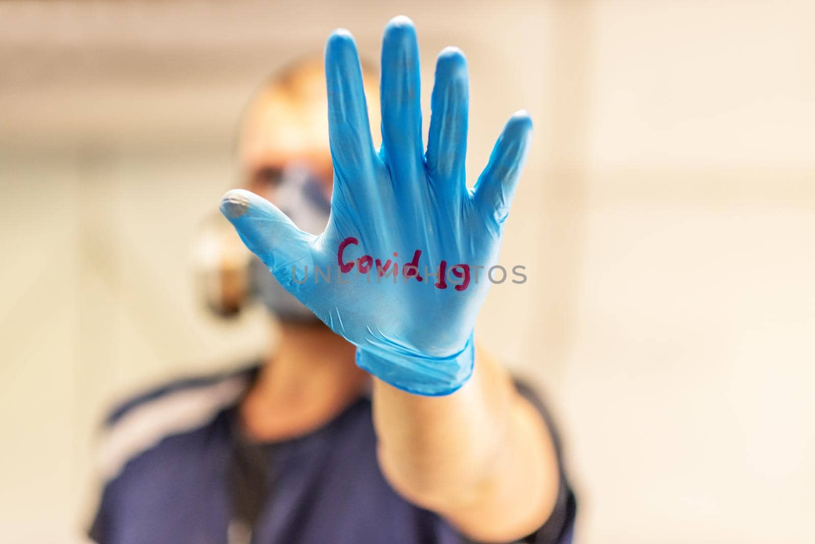 Young man in a protective medical mask and latex gloves holds her hand and shows the viewer on a light isolated background. Concept of coronavirus, clean hands, no virus, stop. Banner. copy space.