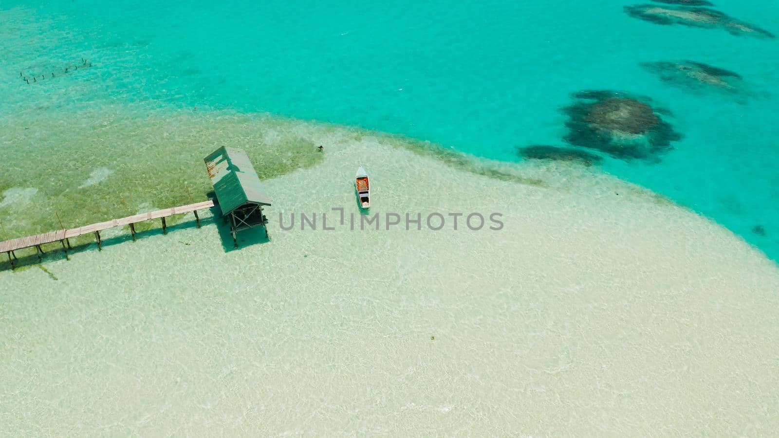 Sandy beach with and azure water, boat of the lagoon,copy space for text, top view. Sea water surface in lagoon. Transparent turquoise ocean water surface. Background texture