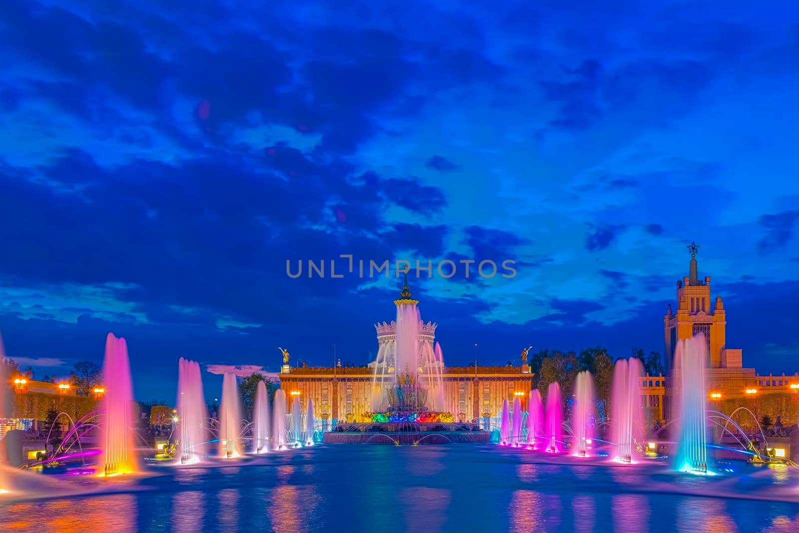 Cascade of fountains with illumination in the regime time, at VDNH in Moscow in the evening. Strong jets beat high with different colors.