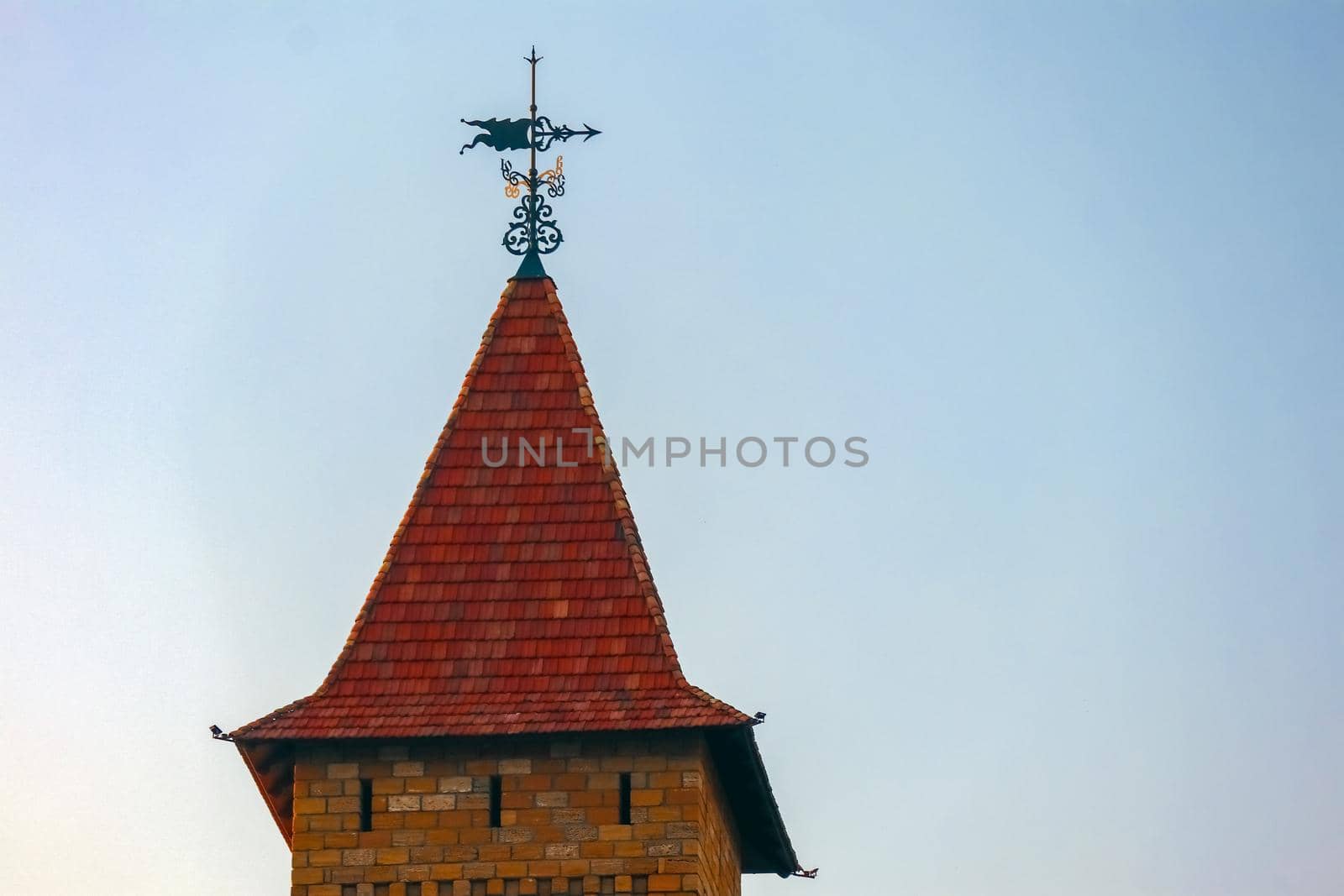 the spire of the tower with a weather vane against the blue sky. High quality photo