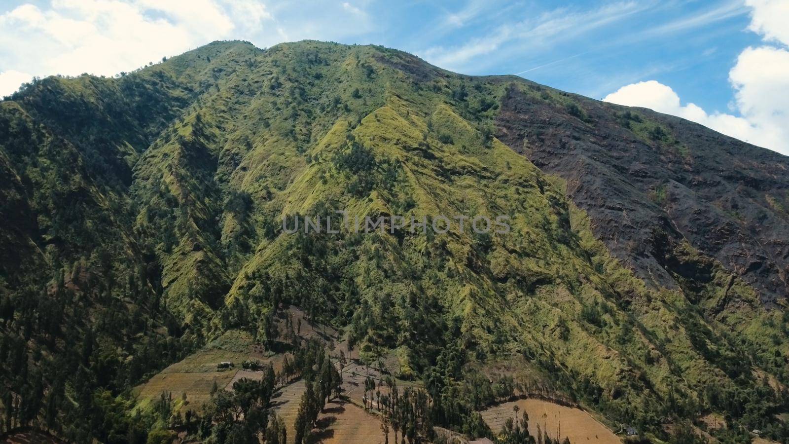 Aerial view Slopes of mountains covered with green tropical forest.Jawa island, Indonesia. High mountain forest with large trees and green grass.Mountain landscape.