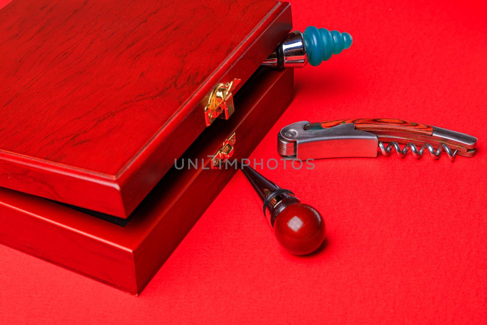 Gift set of corkscrew and removable lids. Wine corks and bottle openers in a wooden box on a red background.