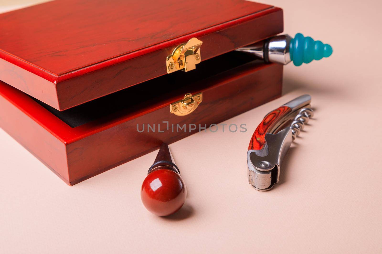 Gift set of corkscrew and removable lids. Wine corks and bottle openers in a wooden box on a pink background.
