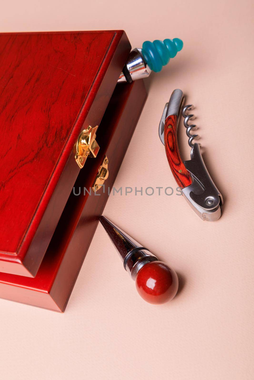 Gift set of corkscrew and removable lids. Wine corks and bottle openers in a wooden box on a pink background.