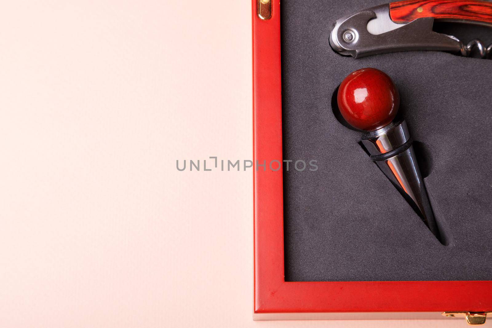 Gift set of corkscrew and removable lids. Wine corks and bottle openers in a wooden box on a pink background.