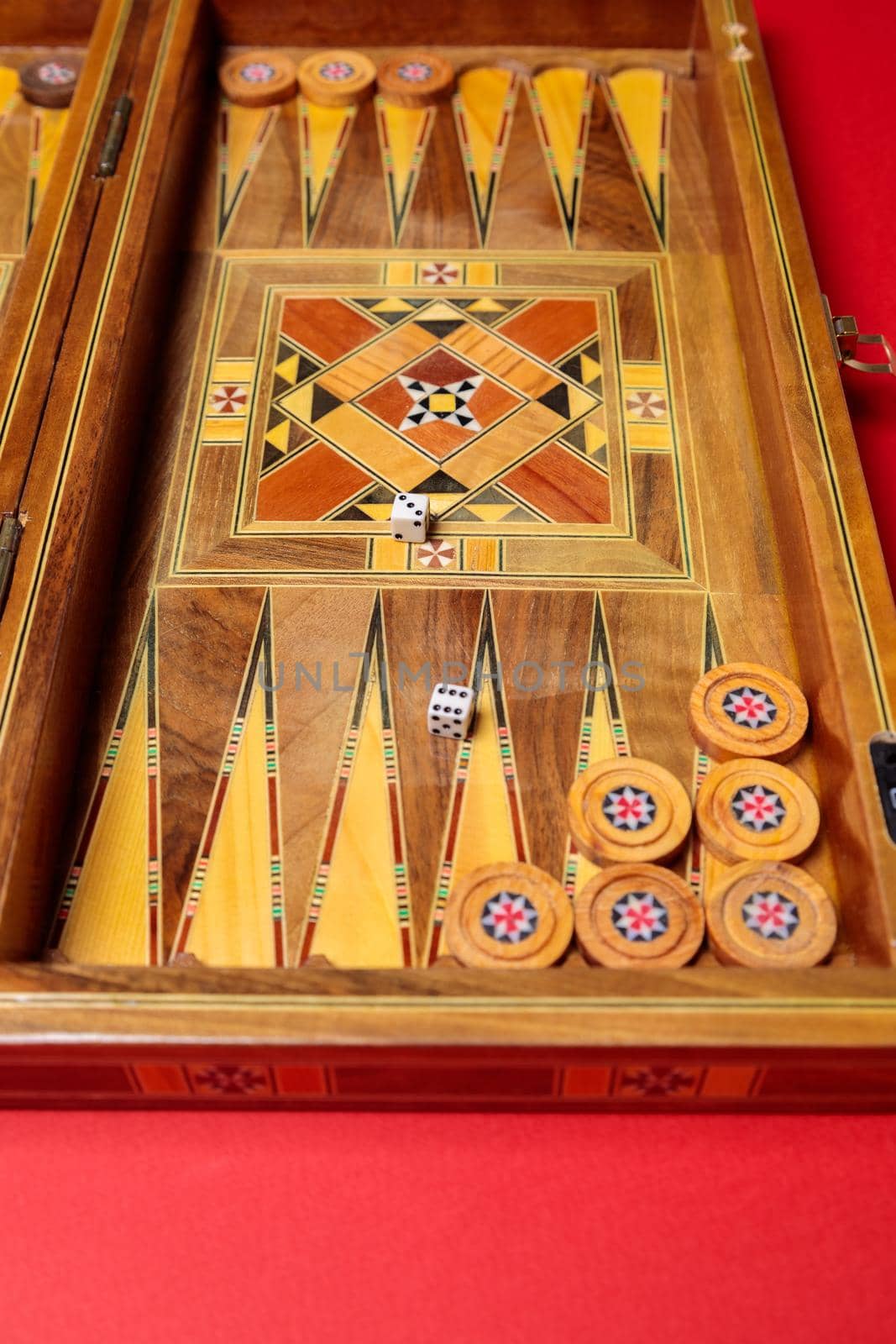 An entertaining game of backgammon on a red background. Checkers, cubes, handmade board