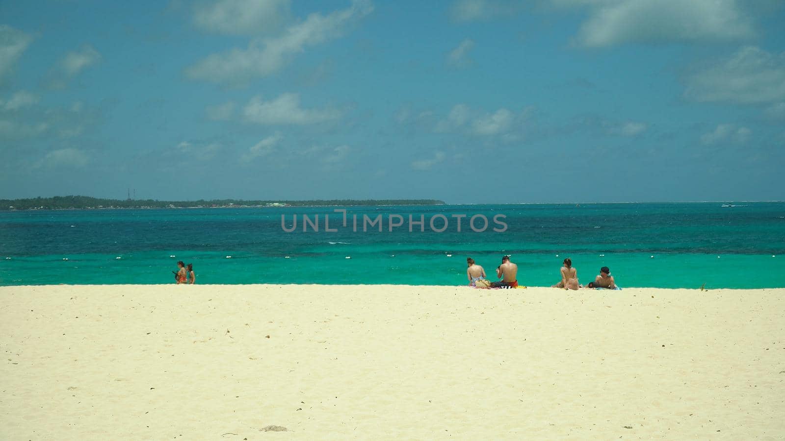 Tropical beach with tourists and clear blue sea. Summer and travel vacation concept. Daco, Philippines