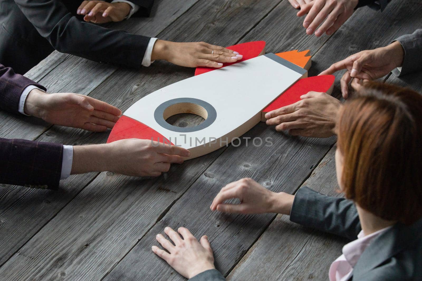 Team of business people with rocket as a sumbol of high risky goals targets success at meeting table