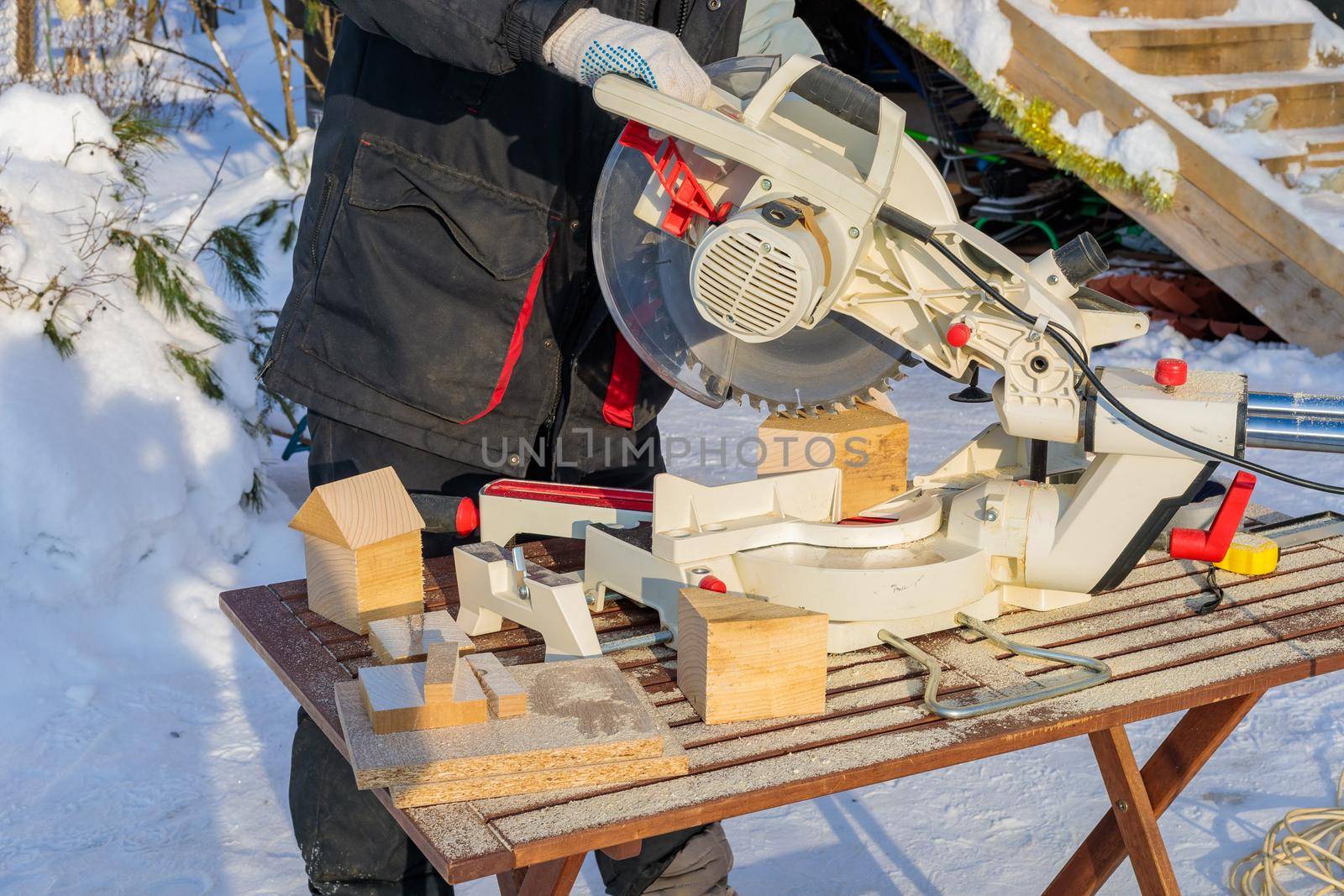 A male worker on the street in winter cuts a block with an angle electric saw with a sharp blade.