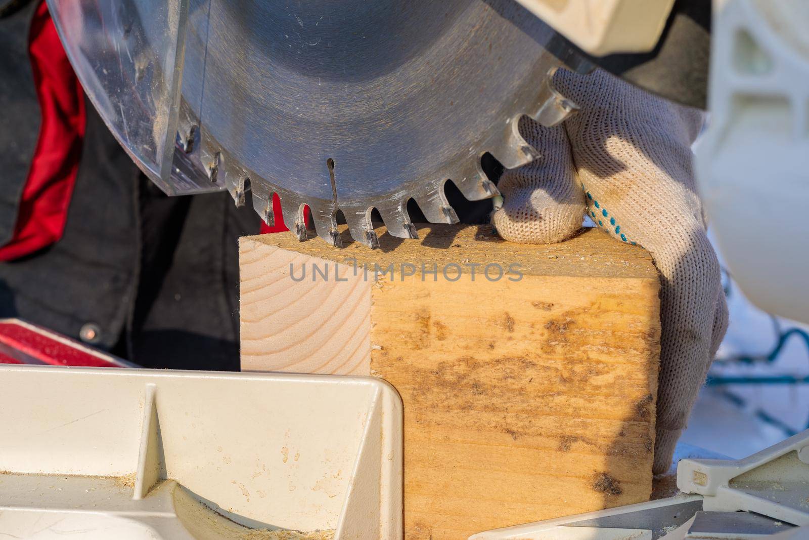 A male worker on the street in winter cuts a block with an angle electric saw with a sharp blade.