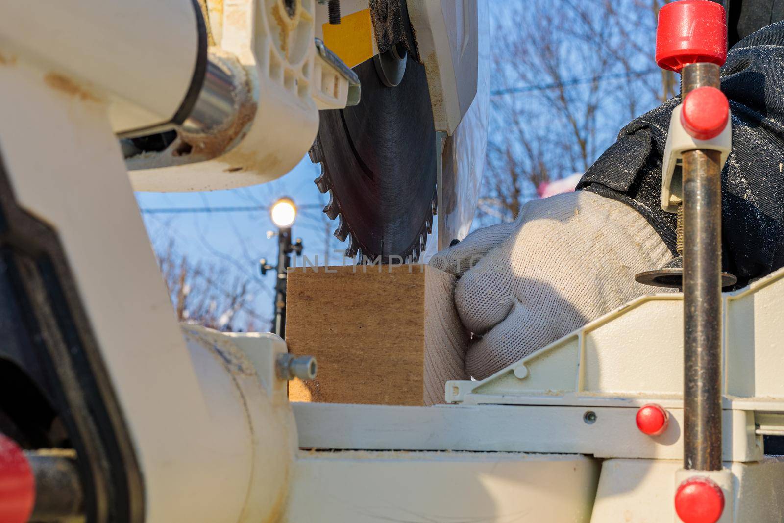 A male worker on the street in winter cuts a block with an angle electric saw with a sharp blade.