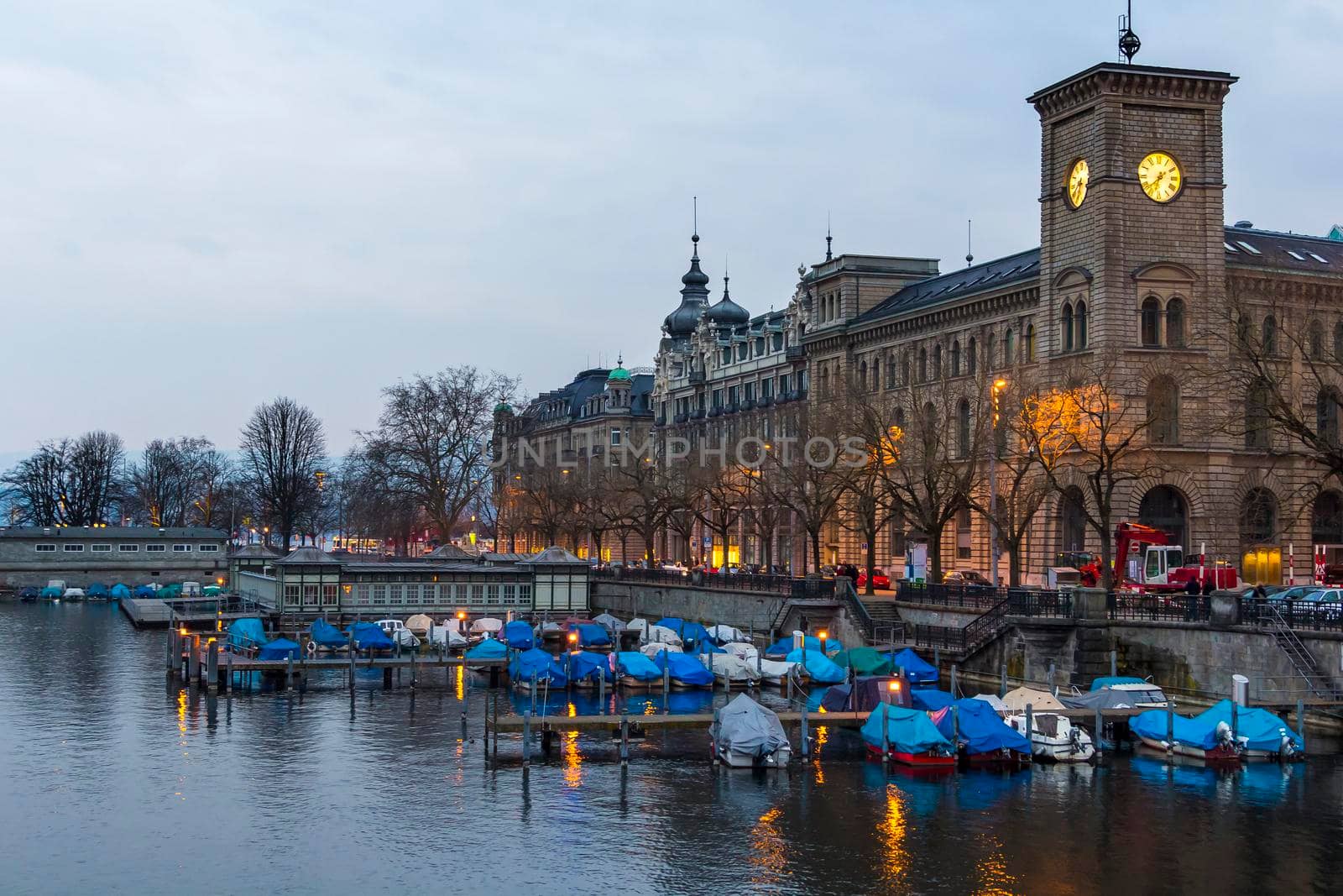 Switzerland, Zurich March 23, 2013 City evening landscape with illumination. Covered boats at the pier, reflected in the water.