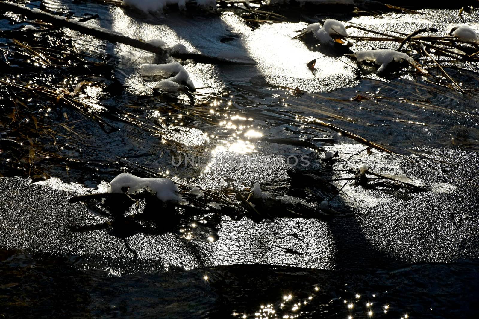 little creek in winter with ice in backlit by Jochen